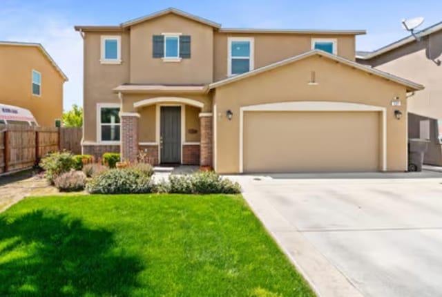 view of front of home with concrete driveway, stucco siding, fence, an attached garage, and a front yard