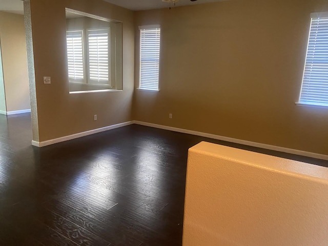 spare room with dark wood-style floors, ceiling fan, and baseboards