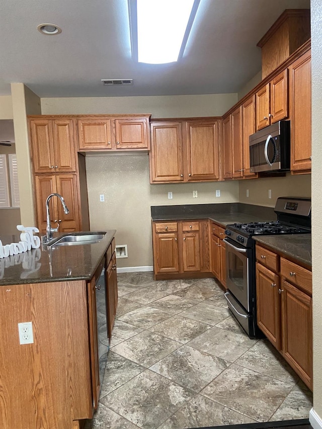 kitchen featuring appliances with stainless steel finishes, brown cabinetry, a sink, and visible vents