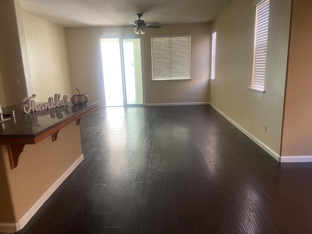 spare room with dark wood-style floors, baseboards, and a ceiling fan