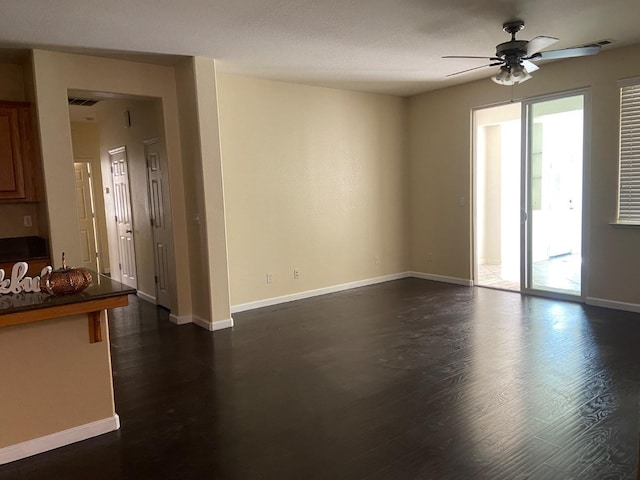 spare room with a ceiling fan, baseboards, and dark wood-type flooring