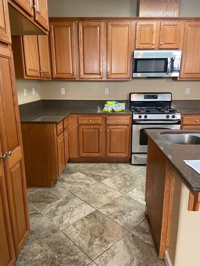 kitchen with dark countertops, appliances with stainless steel finishes, and brown cabinetry