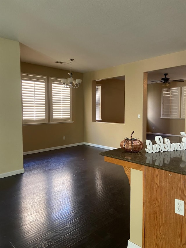 interior space with ceiling fan with notable chandelier, dark wood-style flooring, visible vents, baseboards, and pendant lighting