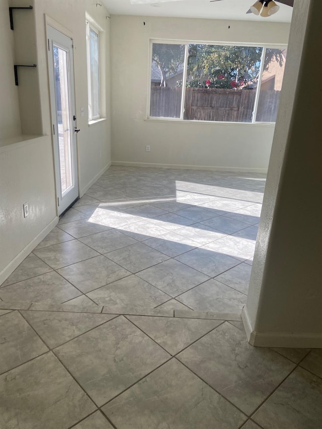 spare room featuring plenty of natural light, a ceiling fan, and baseboards