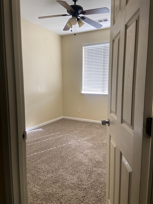 carpeted spare room with ceiling fan, visible vents, and baseboards