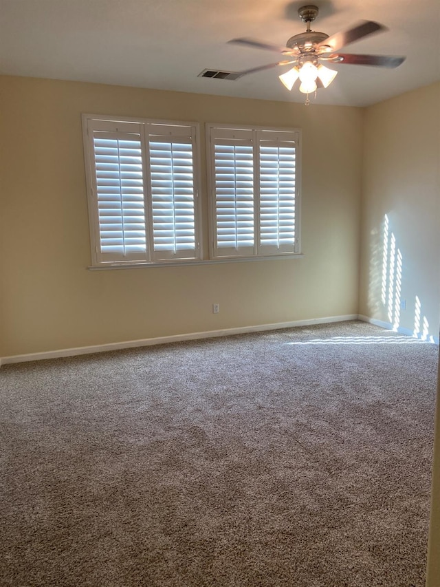 carpeted empty room featuring plenty of natural light, visible vents, baseboards, and a ceiling fan