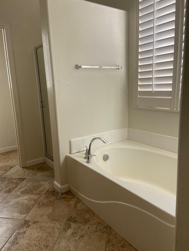 full bath featuring a shower stall, baseboards, and a bath