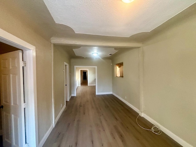 hall with a textured ceiling, wood finished floors, and baseboards