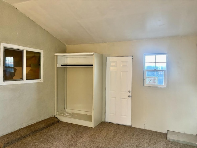 unfurnished bedroom featuring lofted ceiling, a closet, and carpet