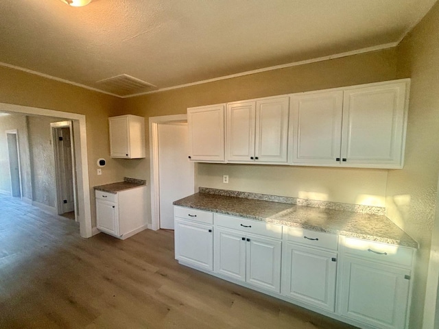 kitchen featuring light wood-style floors, white cabinetry, and crown molding