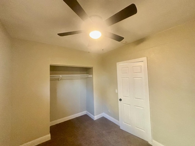 unfurnished bedroom featuring ceiling fan, dark colored carpet, a closet, and baseboards