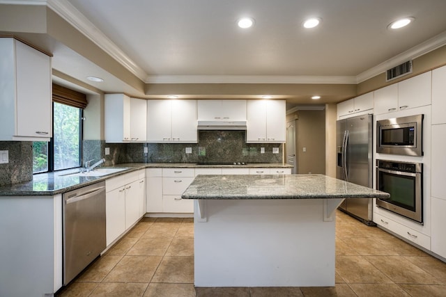 kitchen with white cabinets, stone counters, a kitchen island, and stainless steel appliances