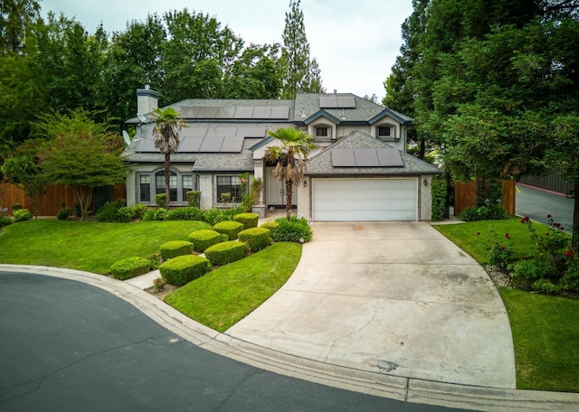 view of front of property with a garage, solar panels, fence, driveway, and a front lawn