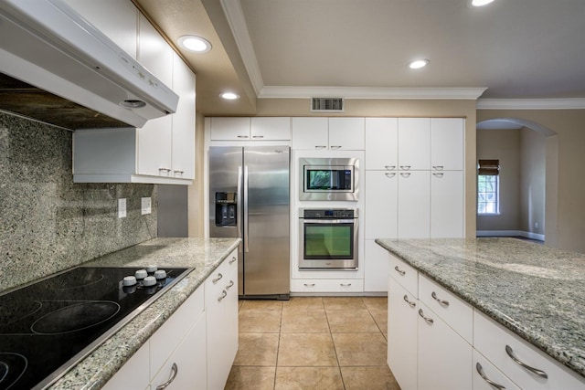 kitchen featuring under cabinet range hood, stainless steel appliances, visible vents, white cabinetry, and ornamental molding