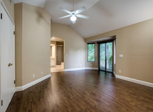 unfurnished room featuring arched walkways, high vaulted ceiling, a ceiling fan, baseboards, and dark wood finished floors