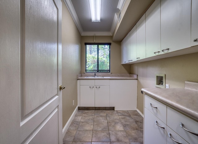 clothes washing area featuring light tile patterned floors, hookup for a washing machine, cabinet space, ornamental molding, and a sink