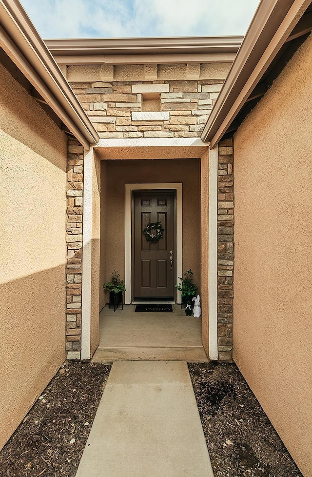 doorway to property with stone siding and stucco siding