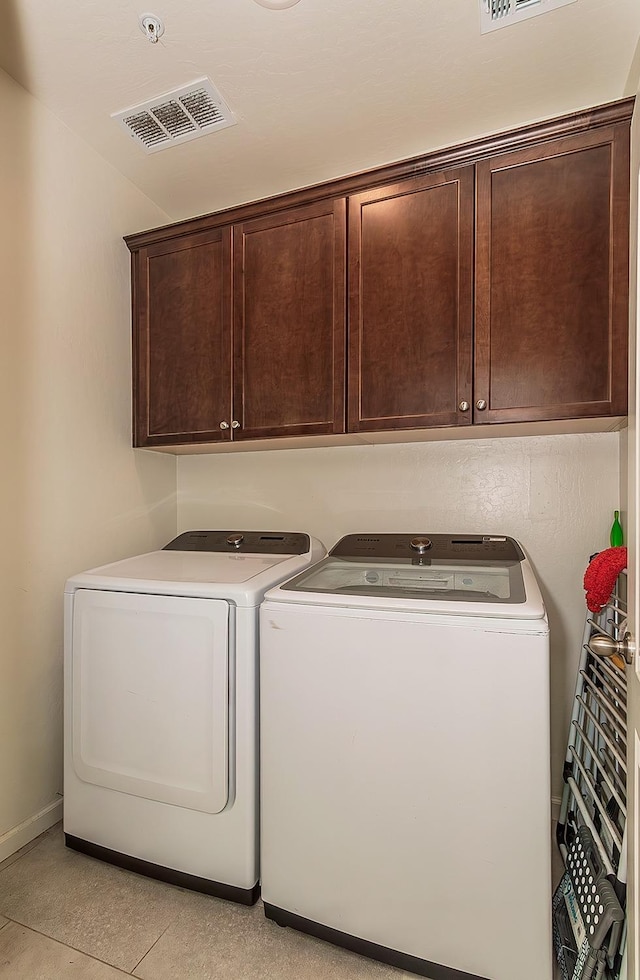 washroom featuring washing machine and dryer, visible vents, and cabinet space