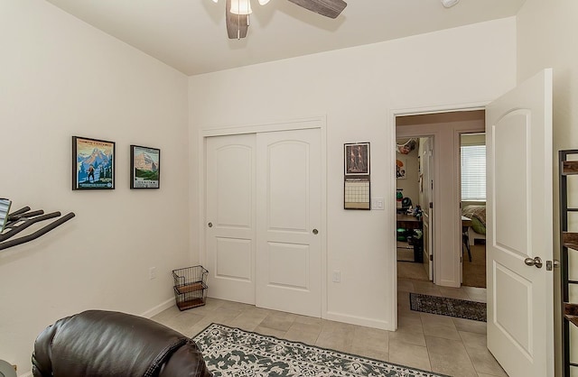 living area with a ceiling fan, baseboards, and light tile patterned floors