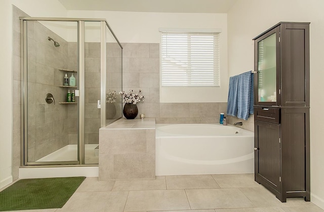 full bathroom with a stall shower, a bath, and tile patterned floors