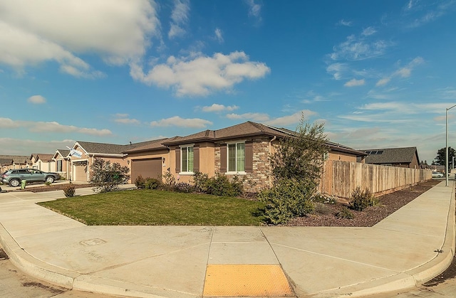 view of front facade featuring a garage, fence, concrete driveway, stone siding, and a front lawn