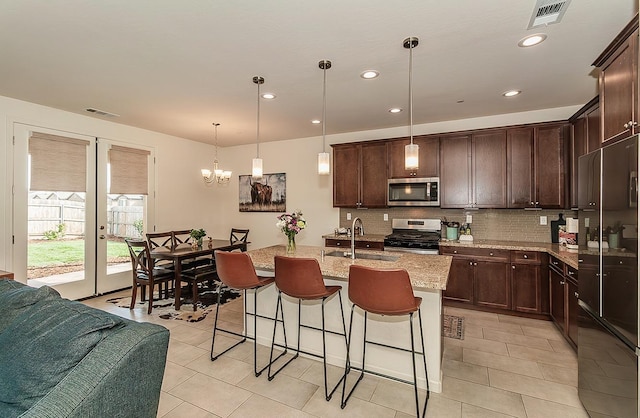 kitchen with a sink, appliances with stainless steel finishes, a center island with sink, and visible vents