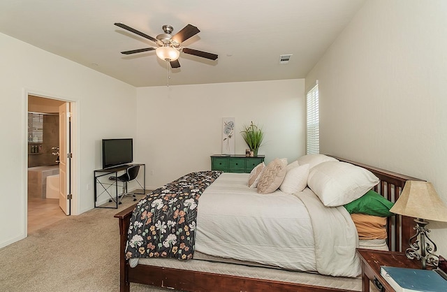 bedroom with ensuite bathroom, a ceiling fan, visible vents, and light colored carpet