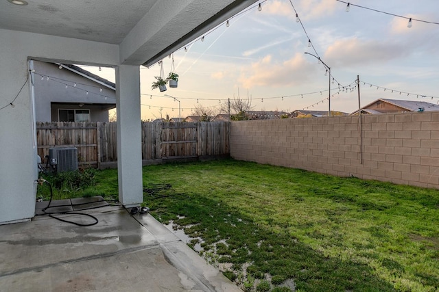 yard at dusk with central air condition unit, a patio area, and a fenced backyard