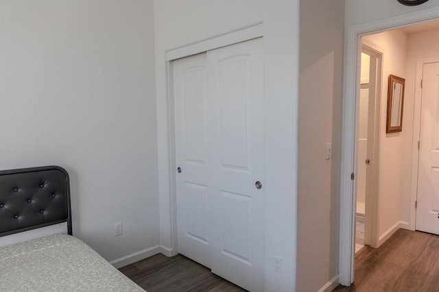 bedroom featuring a closet, dark wood-style flooring, and baseboards