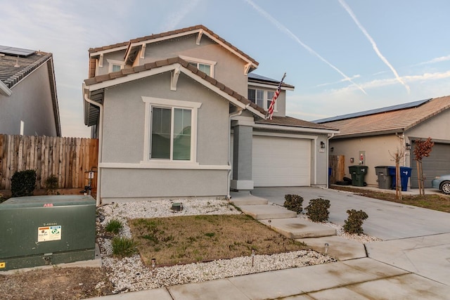 traditional-style home with driveway, an attached garage, fence, and stucco siding