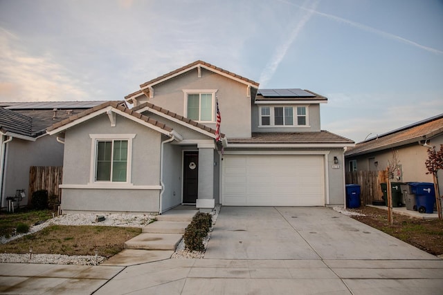 traditional-style home with stucco siding, concrete driveway, an attached garage, roof mounted solar panels, and a tiled roof