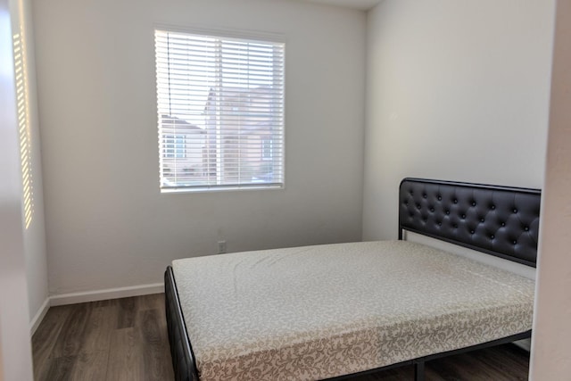 bedroom featuring multiple windows, baseboards, and wood finished floors