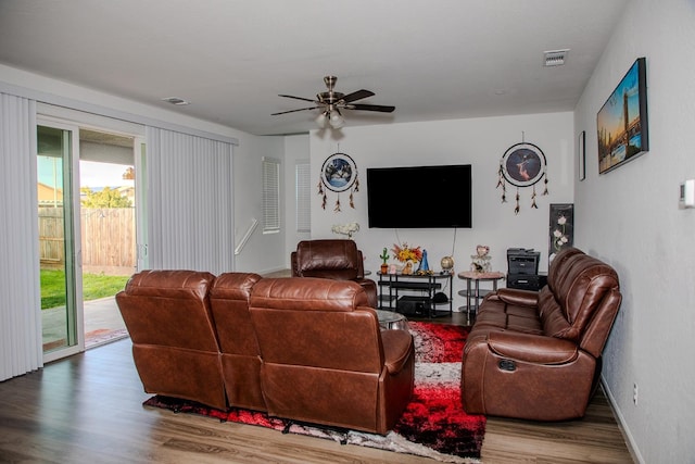 living room featuring visible vents, ceiling fan, baseboards, and wood finished floors