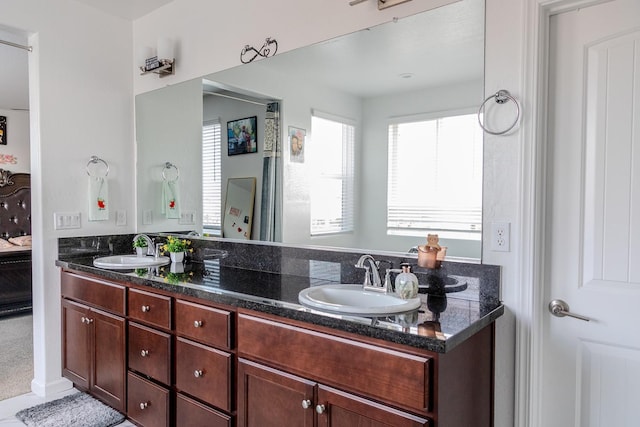 ensuite bathroom featuring double vanity, connected bathroom, and a sink