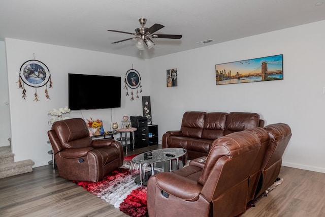 living area with a ceiling fan, visible vents, stairway, and wood finished floors