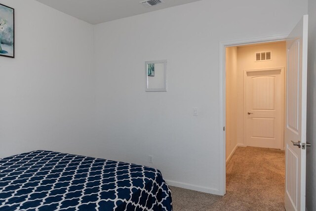 bedroom with baseboards, visible vents, and light colored carpet