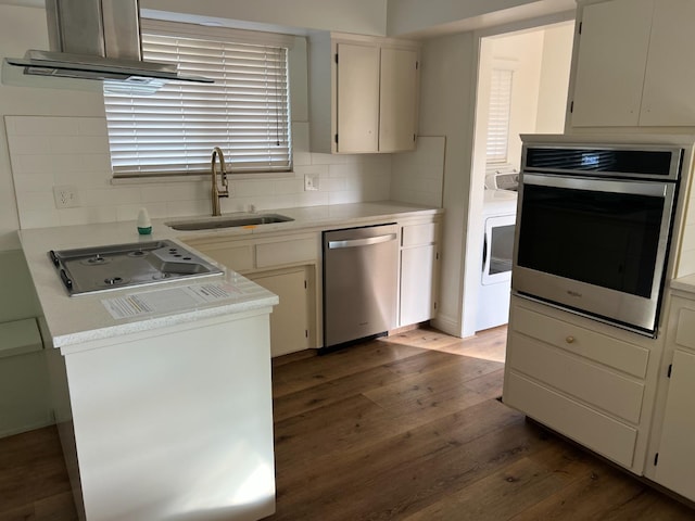 kitchen with dark wood-style flooring, a sink, light countertops, appliances with stainless steel finishes, and decorative backsplash