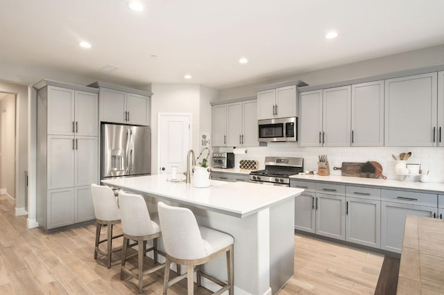 kitchen with gray cabinets, a kitchen bar, appliances with stainless steel finishes, and light countertops