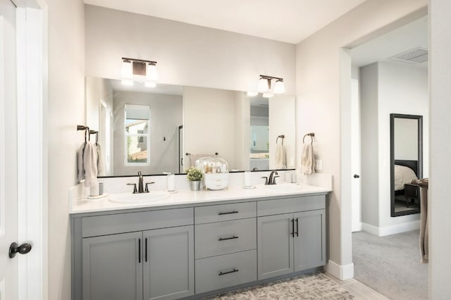 full bath with a sink, double vanity, visible vents, and connected bathroom