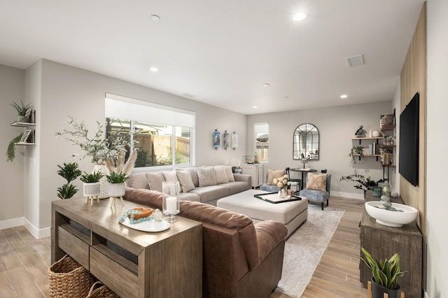 living room featuring light wood-style floors, recessed lighting, visible vents, and baseboards