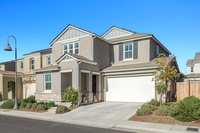 craftsman-style house with a garage, fence, stone siding, driveway, and board and batten siding