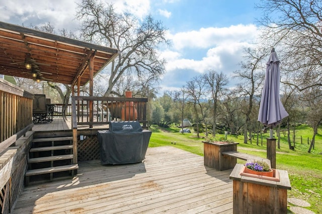 wooden deck with ceiling fan, a yard, and stairs