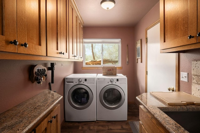 washroom with dark wood finished floors, washing machine and clothes dryer, and cabinet space