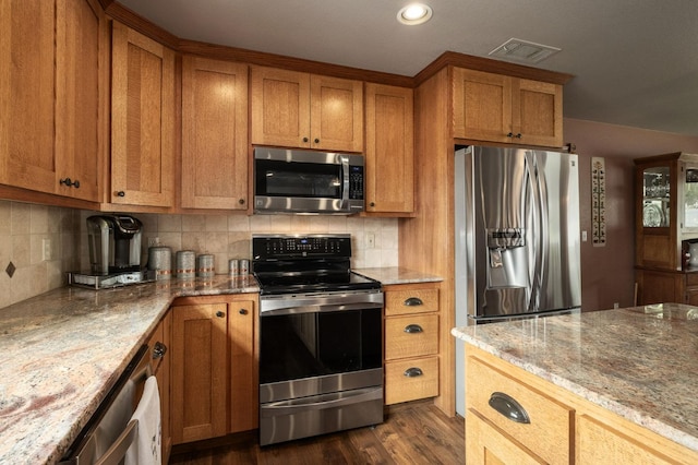 kitchen with stainless steel appliances, light stone counters, visible vents, and tasteful backsplash