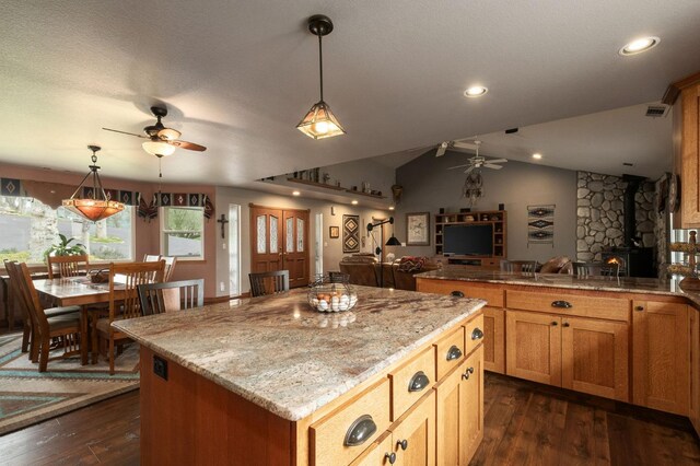 kitchen with pendant lighting, a center island, open floor plan, and a wood stove