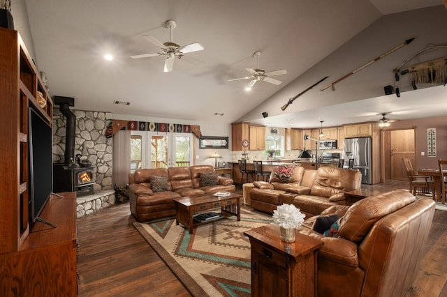 living area with visible vents, a ceiling fan, dark wood-style flooring, a wood stove, and high vaulted ceiling