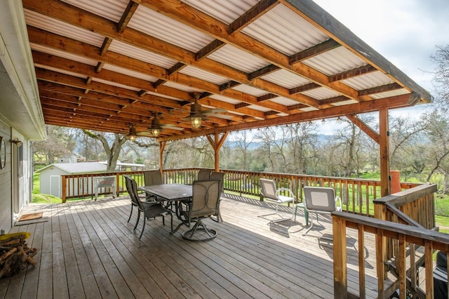 deck with outdoor dining space, an outdoor structure, and a storage unit