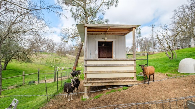 view of outdoor structure featuring fence, an outdoor structure, an exterior structure, and a rural view