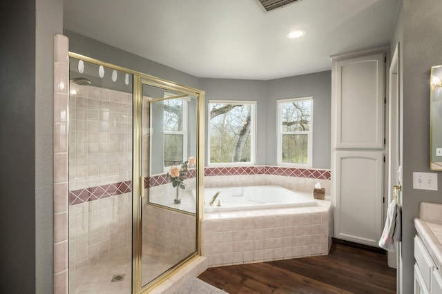 full bathroom with visible vents, a garden tub, a shower stall, and wood finished floors