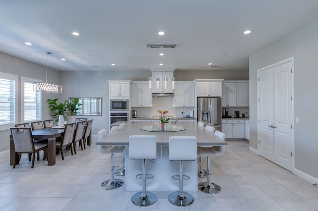 kitchen with oven, white cabinetry, light countertops, built in microwave, and stainless steel fridge